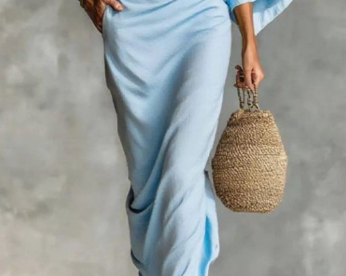 NEWYORKLISTED STYLE COLLECTION: Person wearing a light blue outfit holding a woven bag against a gray background