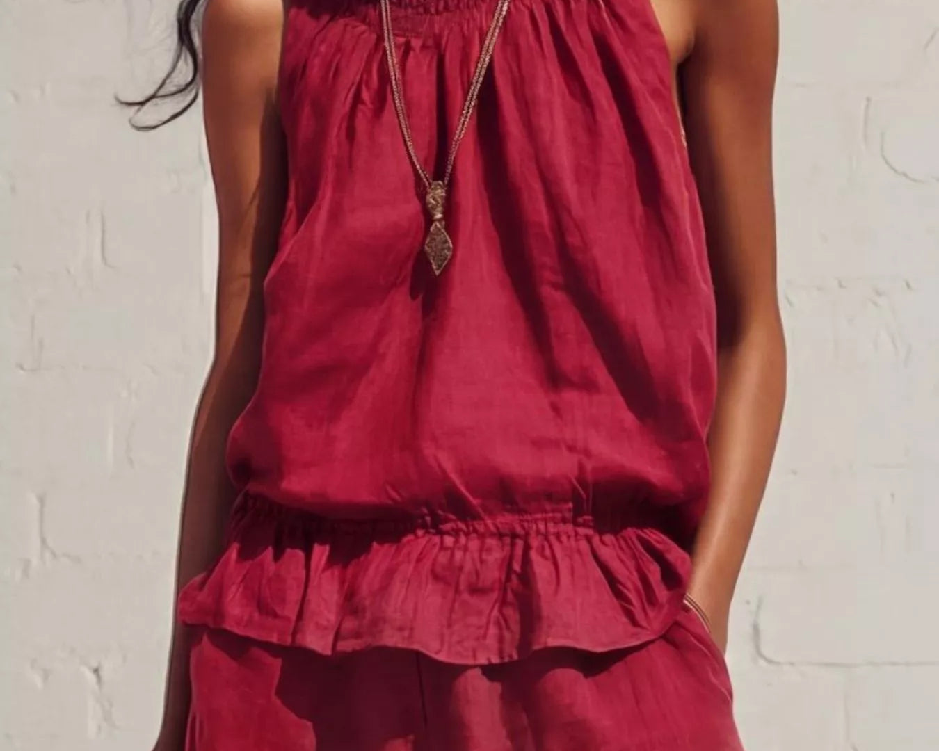 NEWYORKLISTED STYLE COLLECTION: Woman wearing a red sleeveless top and pants against a white brick wall.