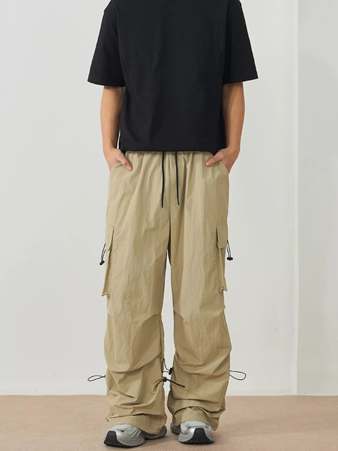 NEWYORKLISTED ATLAS MEN's Collection: Person wearing beige cargo pants and a black t-shirt on a plain background