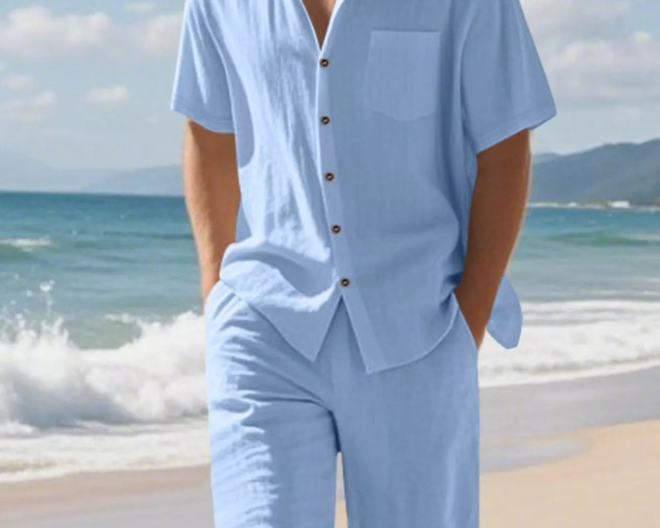 NEWYORKLISTED ATLAS MEN'S COLLECTION: Man wearing a light blue shirt and shorts set on a beach with ocean and sky in the background