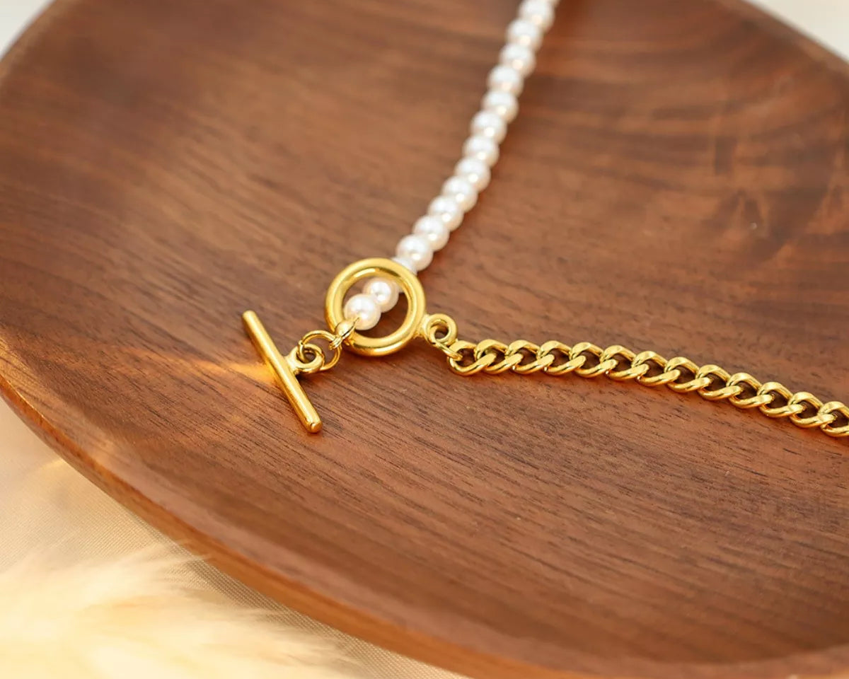 NYLD Glamour Collection by NEWYORKLISTED: Gold necklace with a pearl pendant on a wooden surface