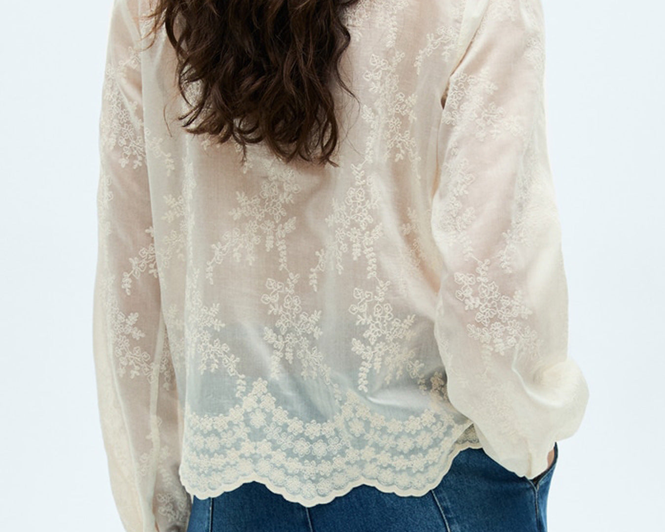 NEWYORKLISTED STYLE COLLECTION: Person wearing a white lace blouse and blue jeans on a light gray background
