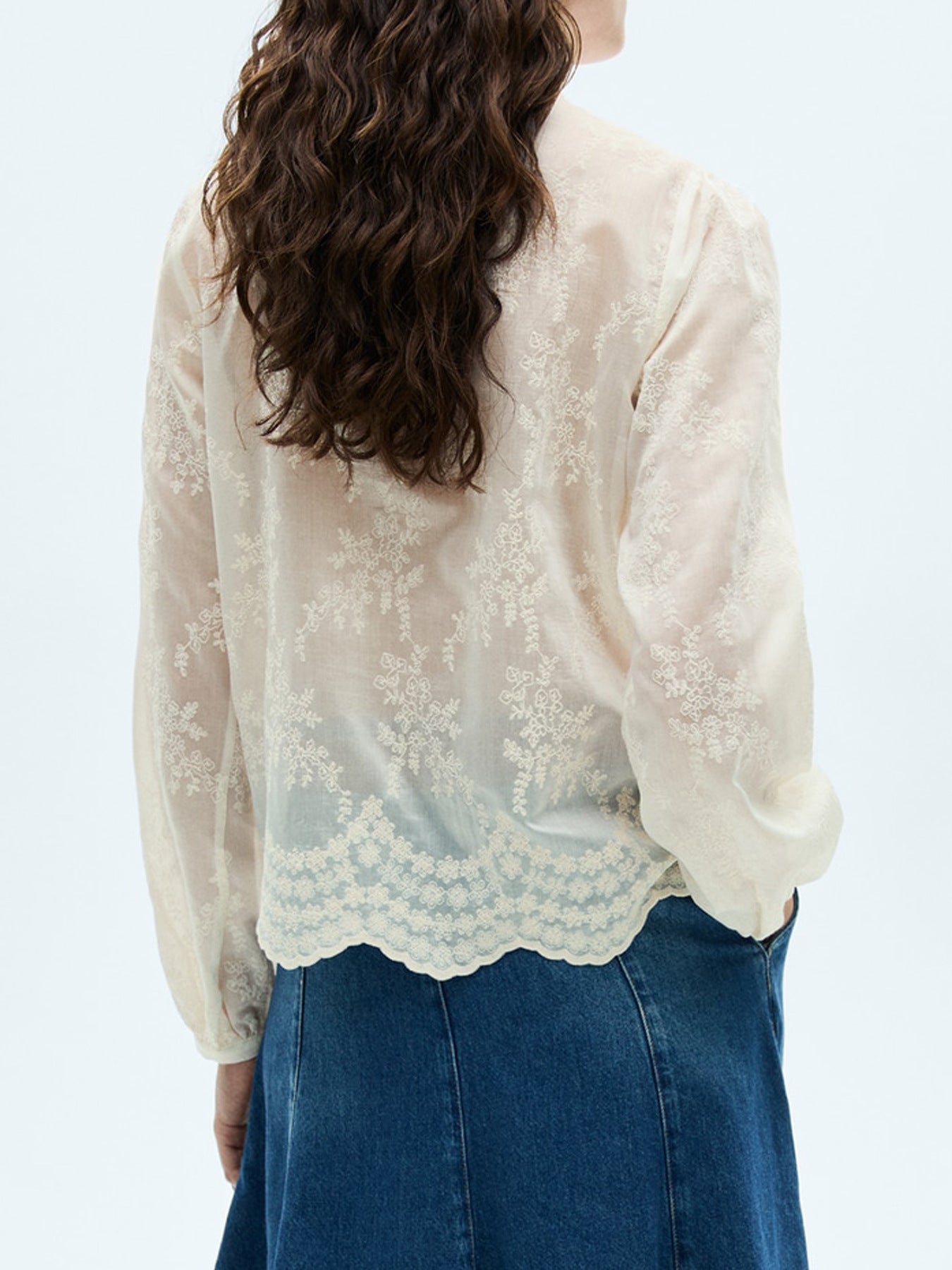 NEWYORKLISTED STYLE COLLECTION: Person wearing a white lace blouse and blue jeans on a light gray background