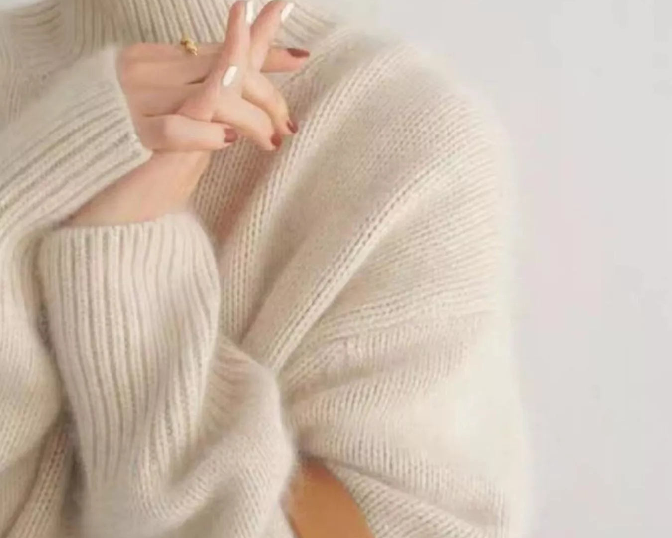 Close-up of a person wearing a beige turtleneck sweater against a white background: NEWYORKLISTED STYLE COLLECTION