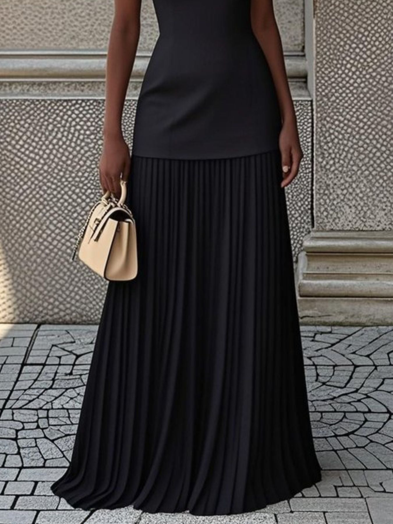 NEWYORKLISTED STYLE COLLECTION: Person wearing a black pleated skirt and holding a beige handbag against a textured wall.
