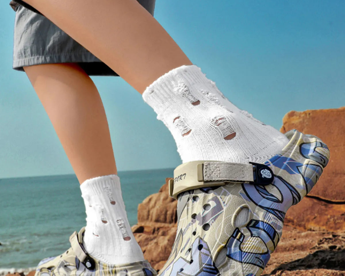 NEWYORKLISTED ATLAS MEN'S COLLECTION: Person wearing patterned sandals and white socks by the ocean