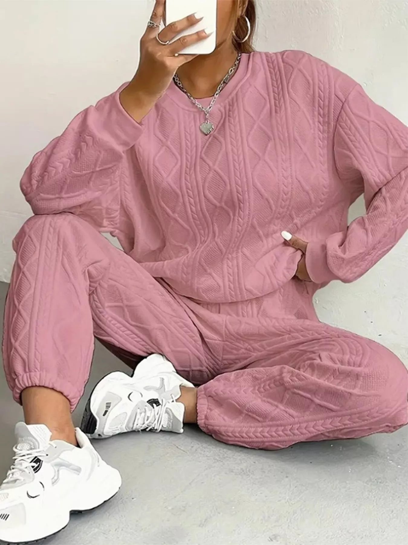 NEWYORKLISTED COMFORT COLLECTION: Person wearing a pink textured tracksuit with white sneakers on a light background