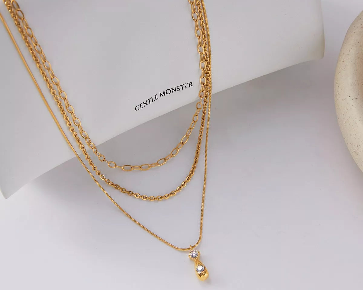 NYLD Glamour Collection by NEWYORKLISTED: Gold chain necklace with a small pendant on a white surface with 'GENTLE MONSTER' branding.