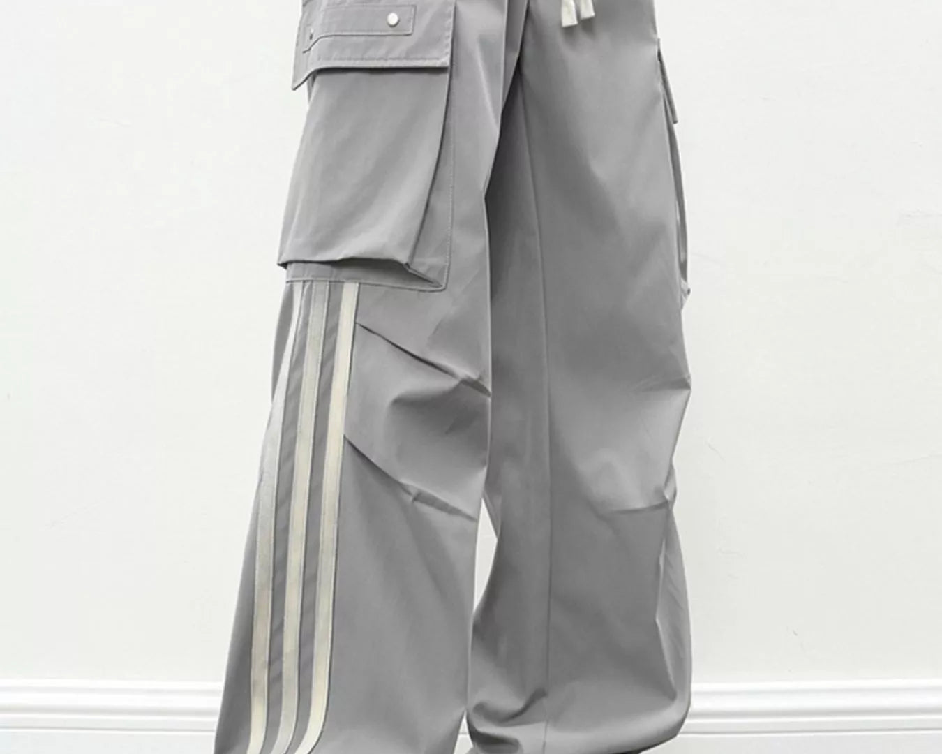 NEWYORKLISTED ATLAS MEN's COLLECTION: Person wearing gray pants with white stripes and white sneakers on a plain background