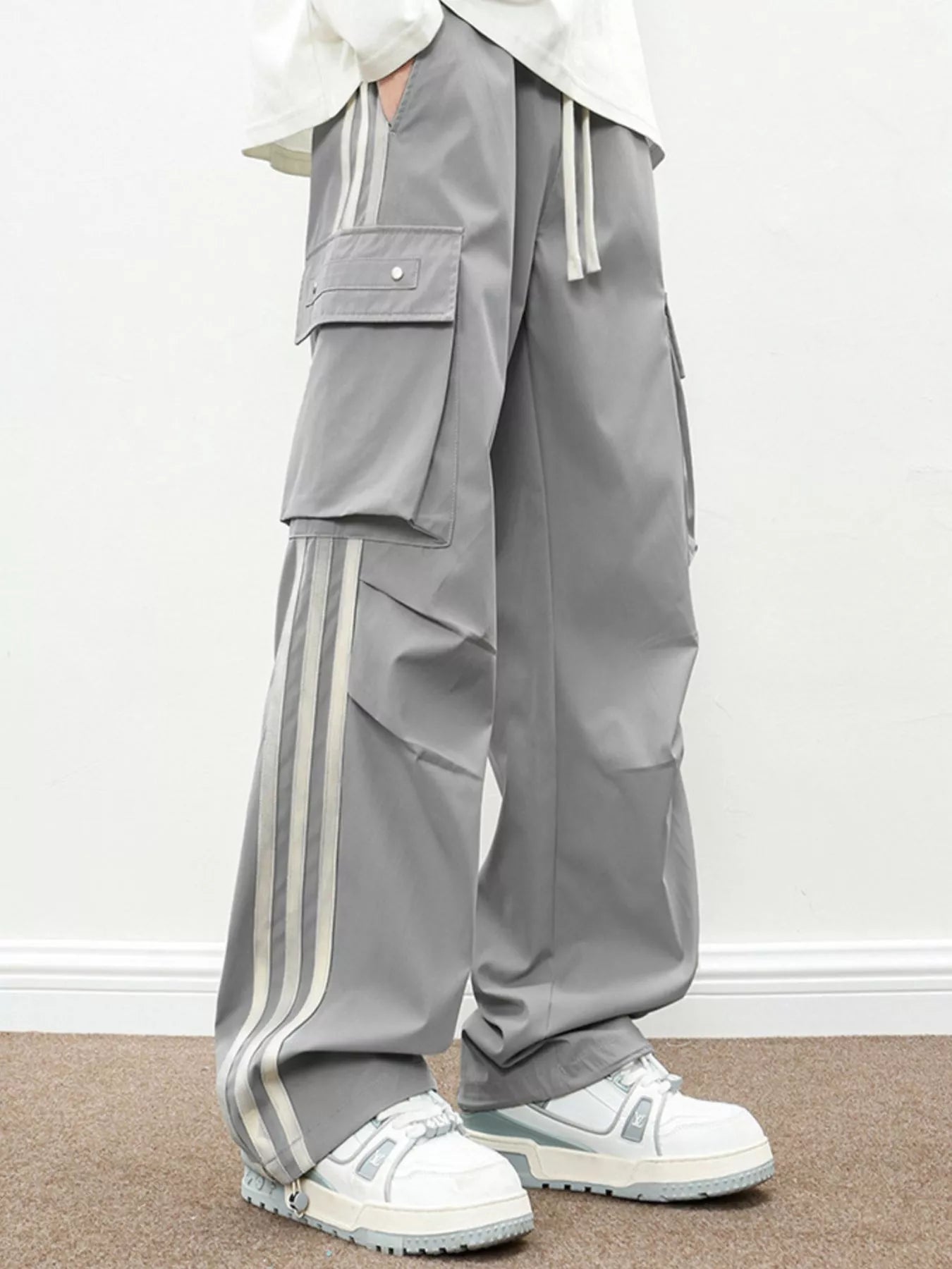 NEWYORKLISTED ATLAS MEN's COLLECTION: Person wearing gray pants with white stripes and white sneakers on a plain background