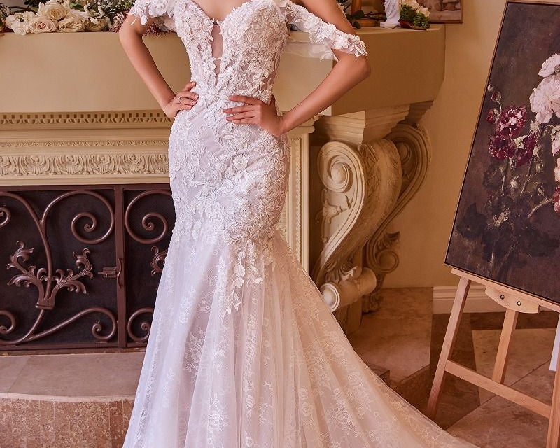 NEWYORKLISTED ELEGANT BRIDE COLLECTION: Woman in a white lace wedding dress standing in an elegant room with decorative elements.