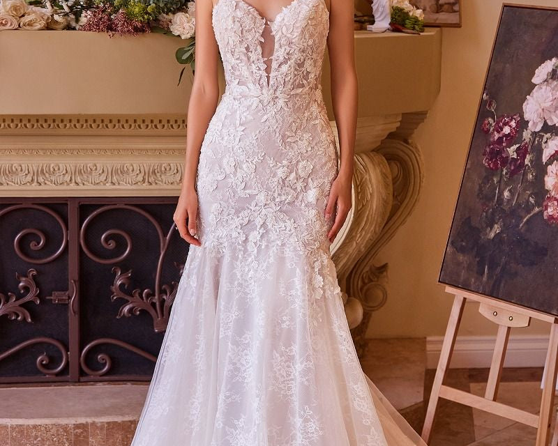 NEWYORKLISTED ELEGANT BRIDE COLLECTION: Woman in a white lace wedding dress standing in an elegant room with decorative elements.