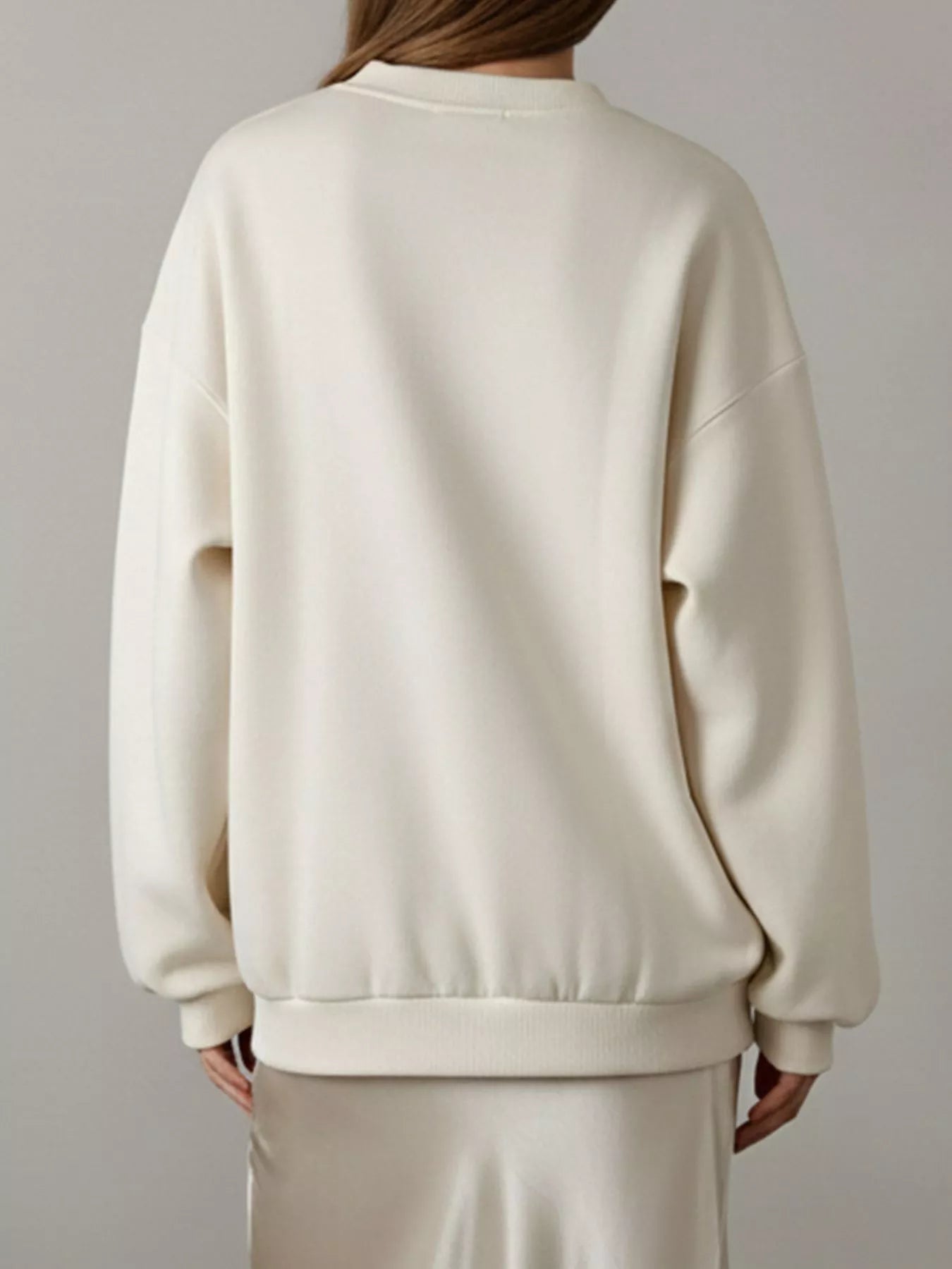 NEWYORKLISTED STYLE COLLECTION: Person wearing a cream-colored sweatshirt against a plain background
