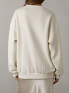 NEWYORKLISTED STYLE COLLECTION: Person wearing a cream-colored sweatshirt against a plain background