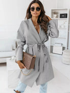 NEWYORKLISTED STYLE COLLECTION: Woman wearing a gray coat in a modern living room