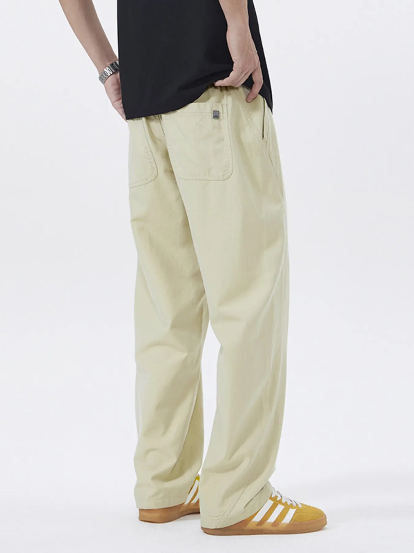 NEWYORKLISTED ATLAS MEN's COLLECTION: Person wearing beige pants and a black top on a white background