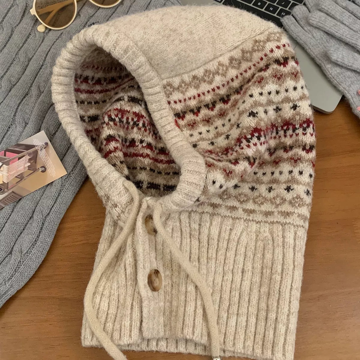 NEWYORKLISTED STYLE COLLECTION: Drawstring Knitted Winter Hat – Cozy, Chic & Cold-Weather Ready: Knitted cardigan with patterned hood on a wooden surface