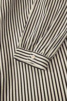 NEWYORKLISTED STYLE COLLECTION: Close-up of a black and white striped shirt with a button detail.