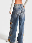 NEWYORKLISTED STYLE COLLECTION: Blue jeans with floral embellishments on a white background