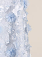 NEWYORKLISTED STYLE COLLECTION: Close-up of a decorative floral garland with light blue and white flowers on a neutral background