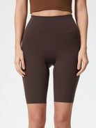 Person wearing brown high-waisted shorts on a plain background