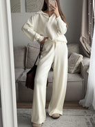 NEWYORKLISTED Comfort Collection: Person wearing a white outfit taking a mirror selfie in a living room.