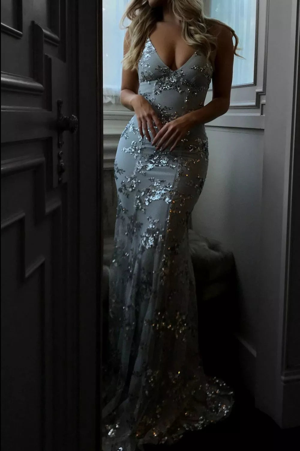 Woman wearing a silver sequin evening gown in a room.