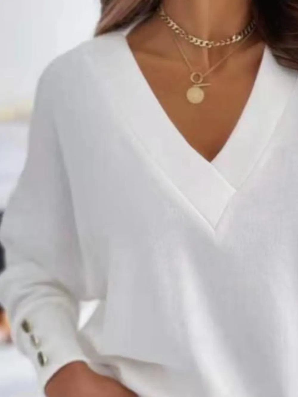 NEWYORKLISTED STYLE COLLECTION: White blouse with a V-neckline worn by a person, with a blurred background
