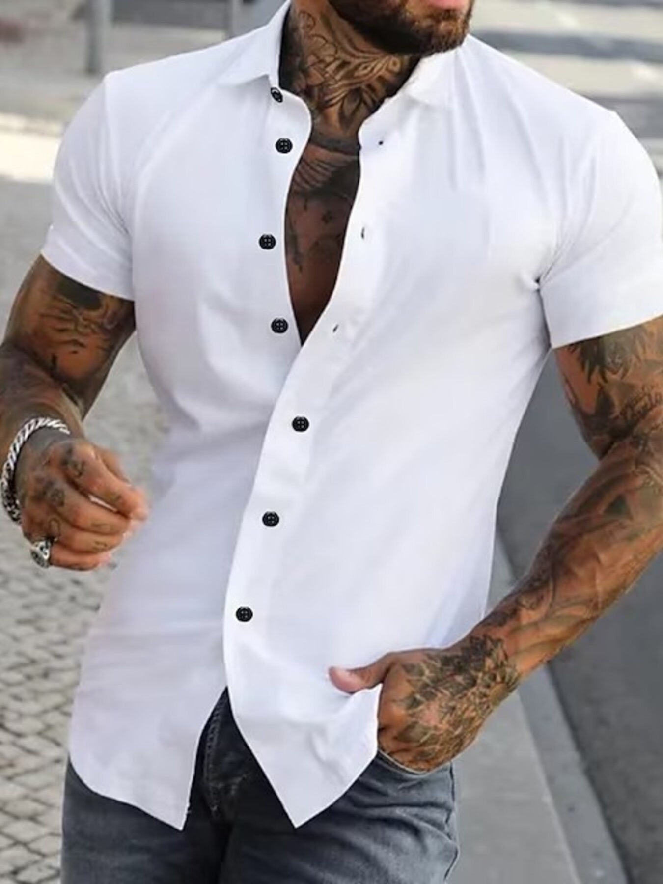 NEWYORKLISTED ATLAS MEN's COLLECTION: Man wearing a white short-sleeve button-up shirt with black buttons, standing outdoors.