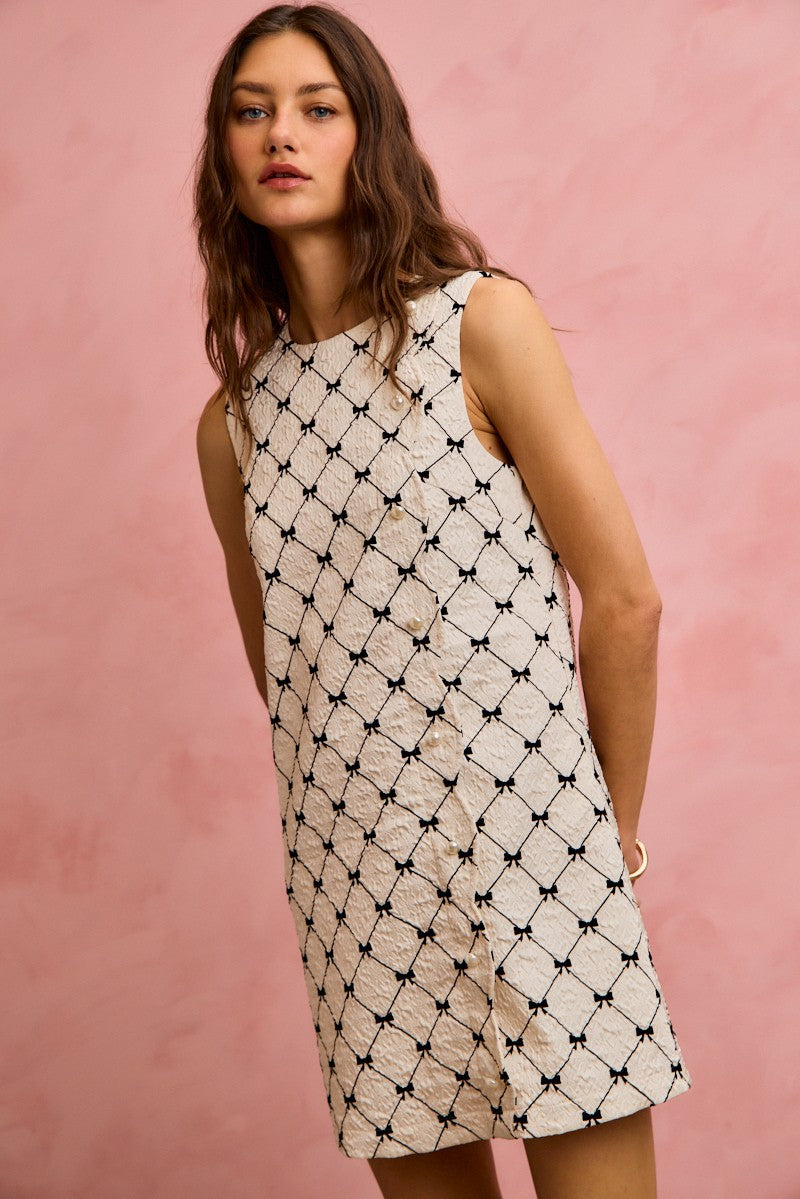 NEWYORKLISTED STYLE COLLECTION: Woman wearing a sleeveless dress with a geometric pattern against a pink background