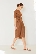 Woman wearing a brown dress against a white background: NEWYORKLISTED STYLE COLLECTION