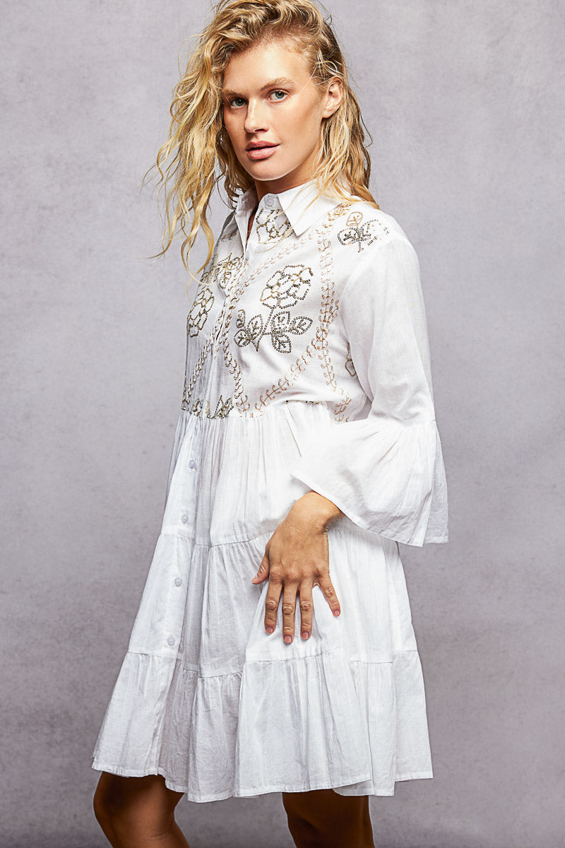 NEWYORKLISTED STYLE COLLECTION: Woman wearing a white embroidered dress against a gray background