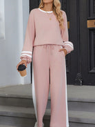 NEWYORKLISTED Comfort Collection: Woman wearing a pink outfit with white stripes, standing on steps.