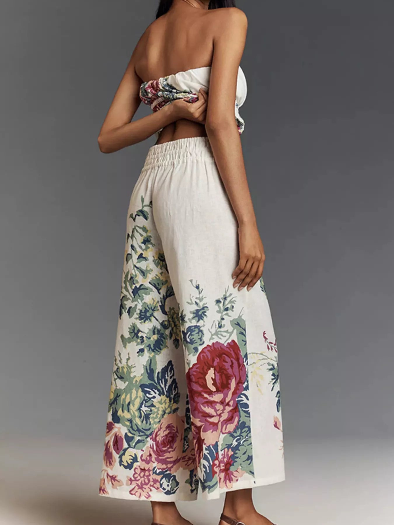 NEWYORKLISTED STYLE COLLECTION: Woman wearing a strapless top and floral pants against a gray background