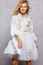 NEWYORKLISTED STYLE COLLECTION: Woman wearing a white embroidered dress against a gray background