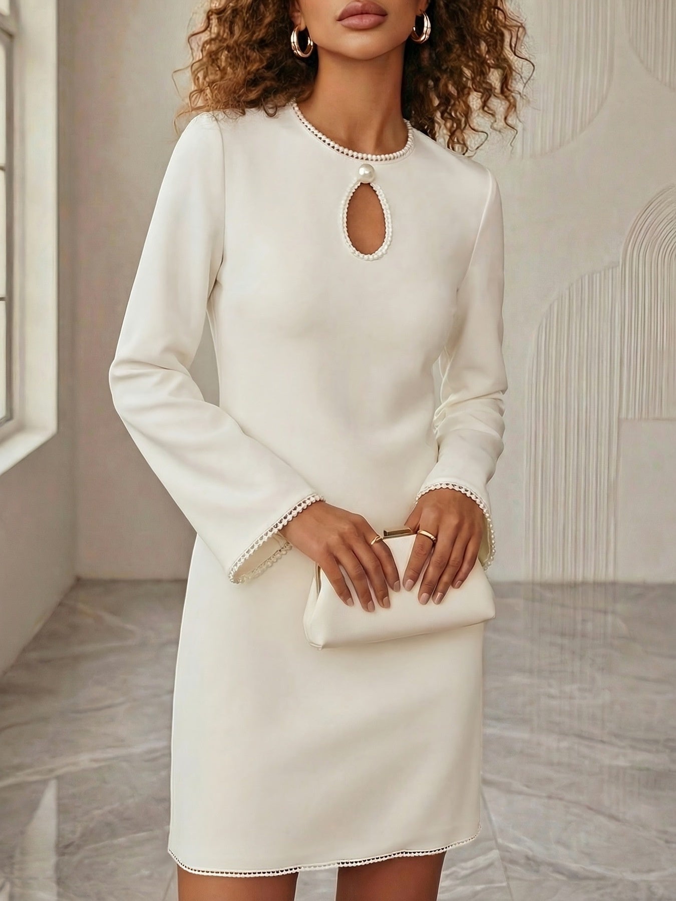 NEWYORKLISTED STYLE COLLECTION: Woman wearing a white dress with a cut-out design in a neutral setting