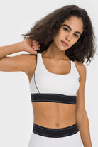 NEWYORKLISTED ACTIVEWEAR COLLECTION: Woman wearing a white sports bra with black accents on a plain background
