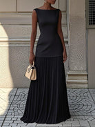 NEWYORKLISTED STYLE COLLECTION: Woman wearing a black dress holding a beige handbag against a textured wall.