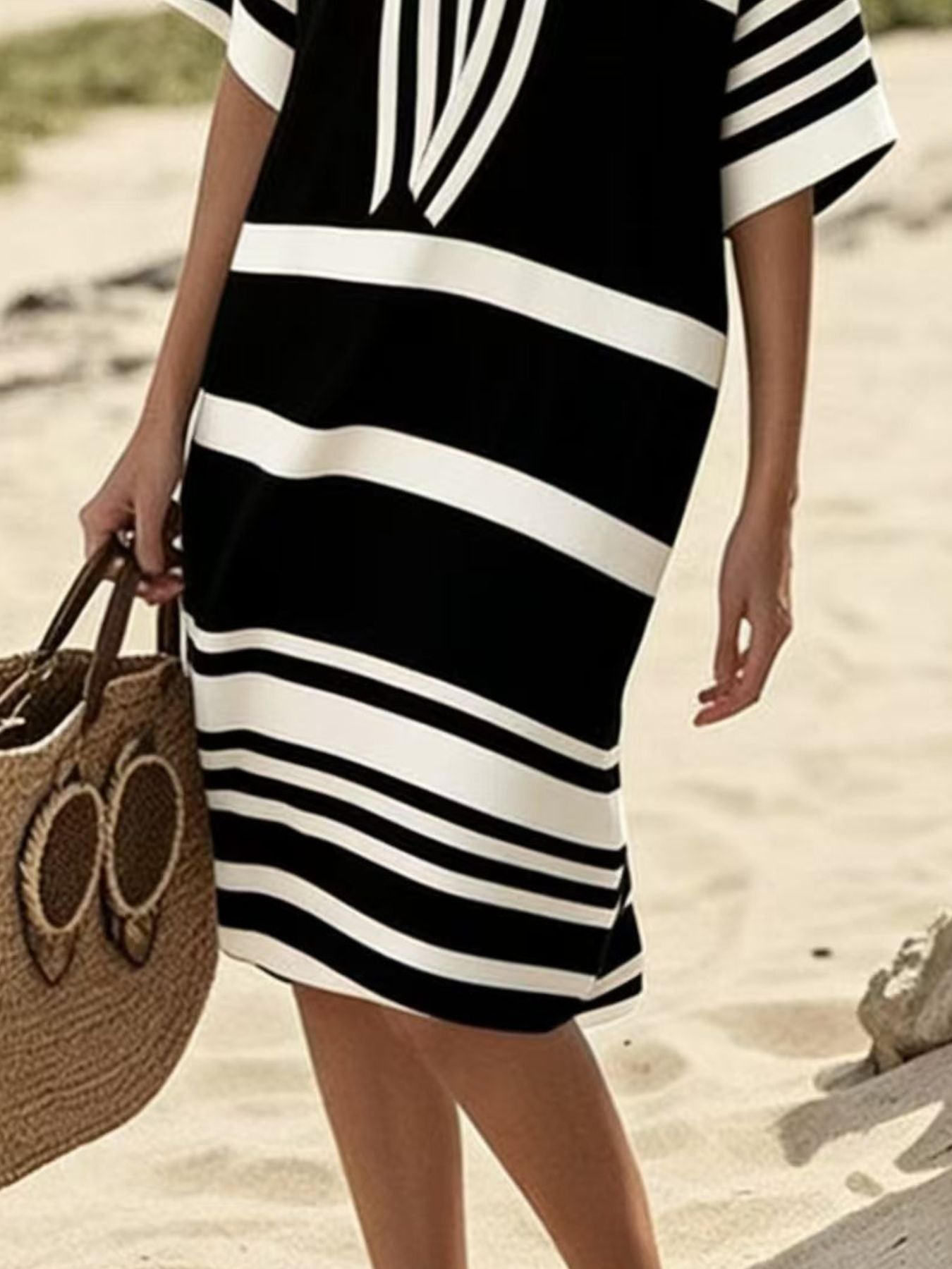 NEWYORKLISTED STYLE COLLECTION: Person wearing a black and white striped dress on a beach.
