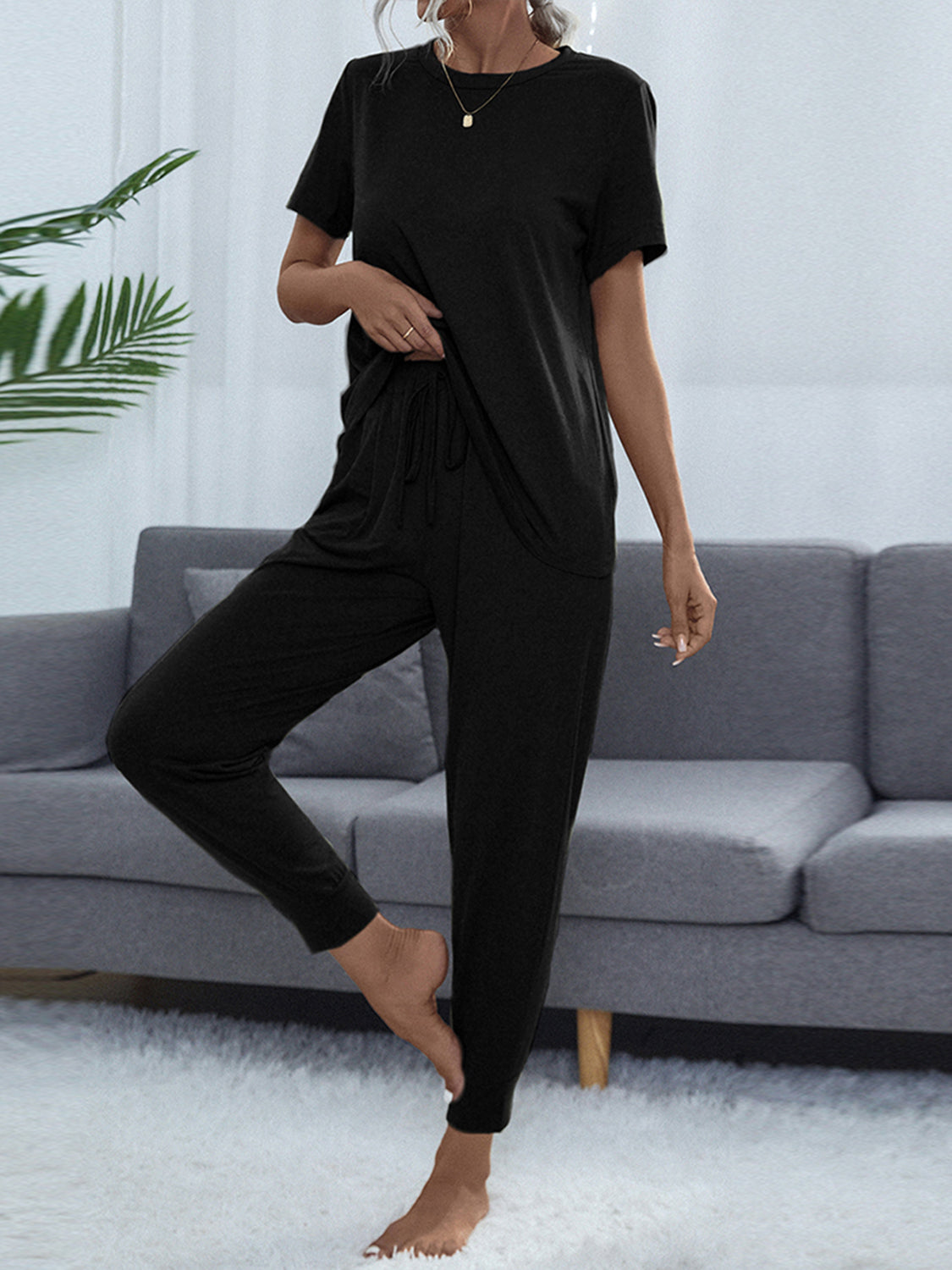 NEWYORKLISTED Intimate Apparel: Person wearing a black outfit standing in front of a gray sofa.