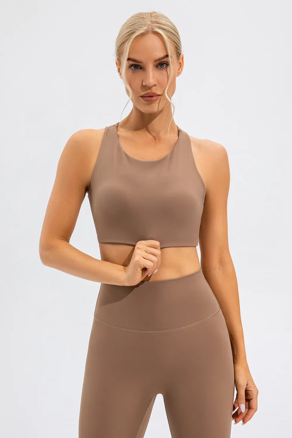 NEWYORKLISTED ACTIVEWEAR COLLECTION: Woman wearing a brown athletic outfit on a light gray background