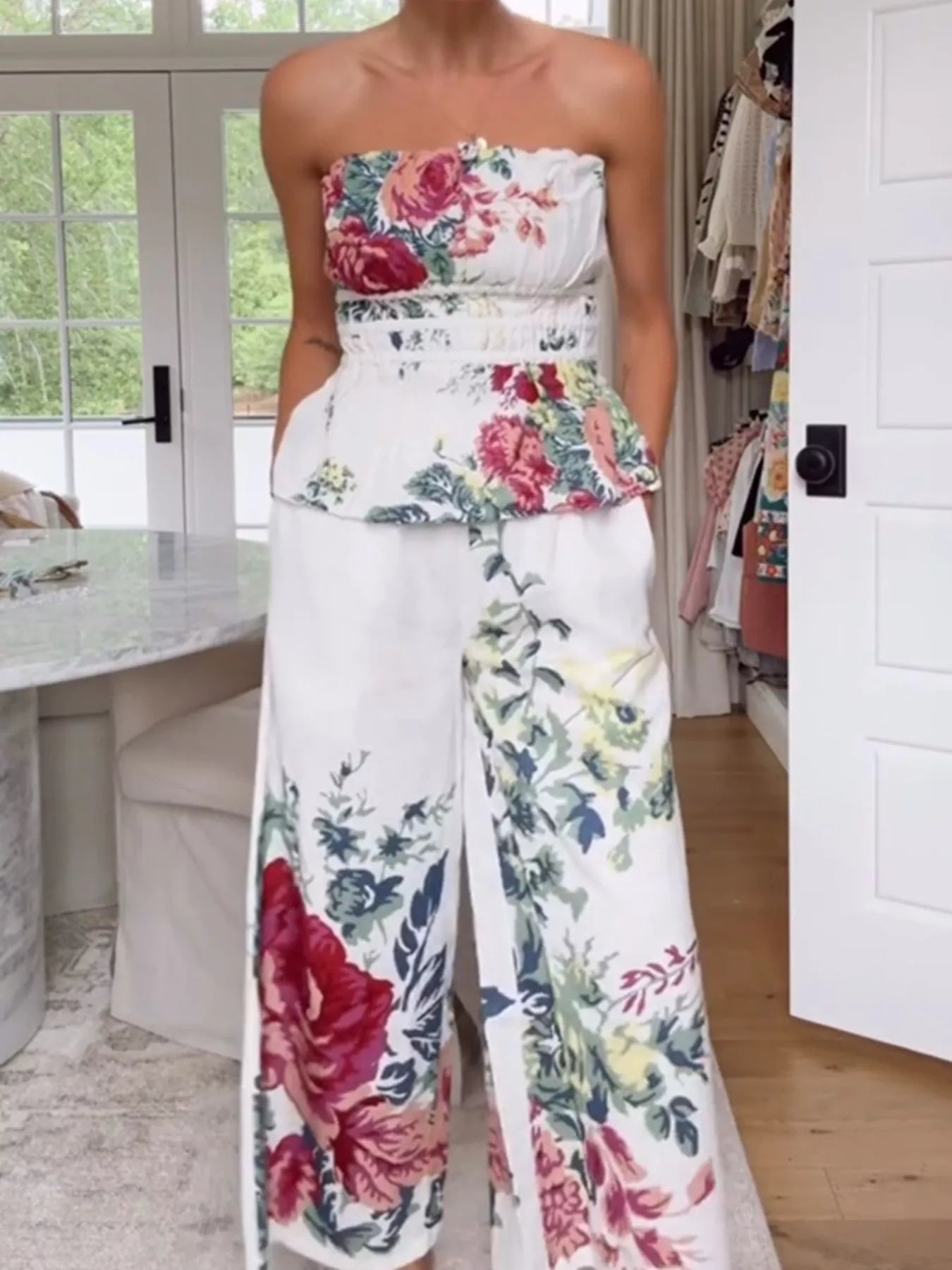 NEWYORKLISTED STYLE COLLECTION: Person wearing a floral strapless top and wide-leg pants in a room with a desk and window.
