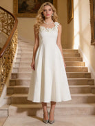NEWYORKLISTED STYLE COLLECTION: Woman in a white dress standing on a staircase in an elegant interior setting