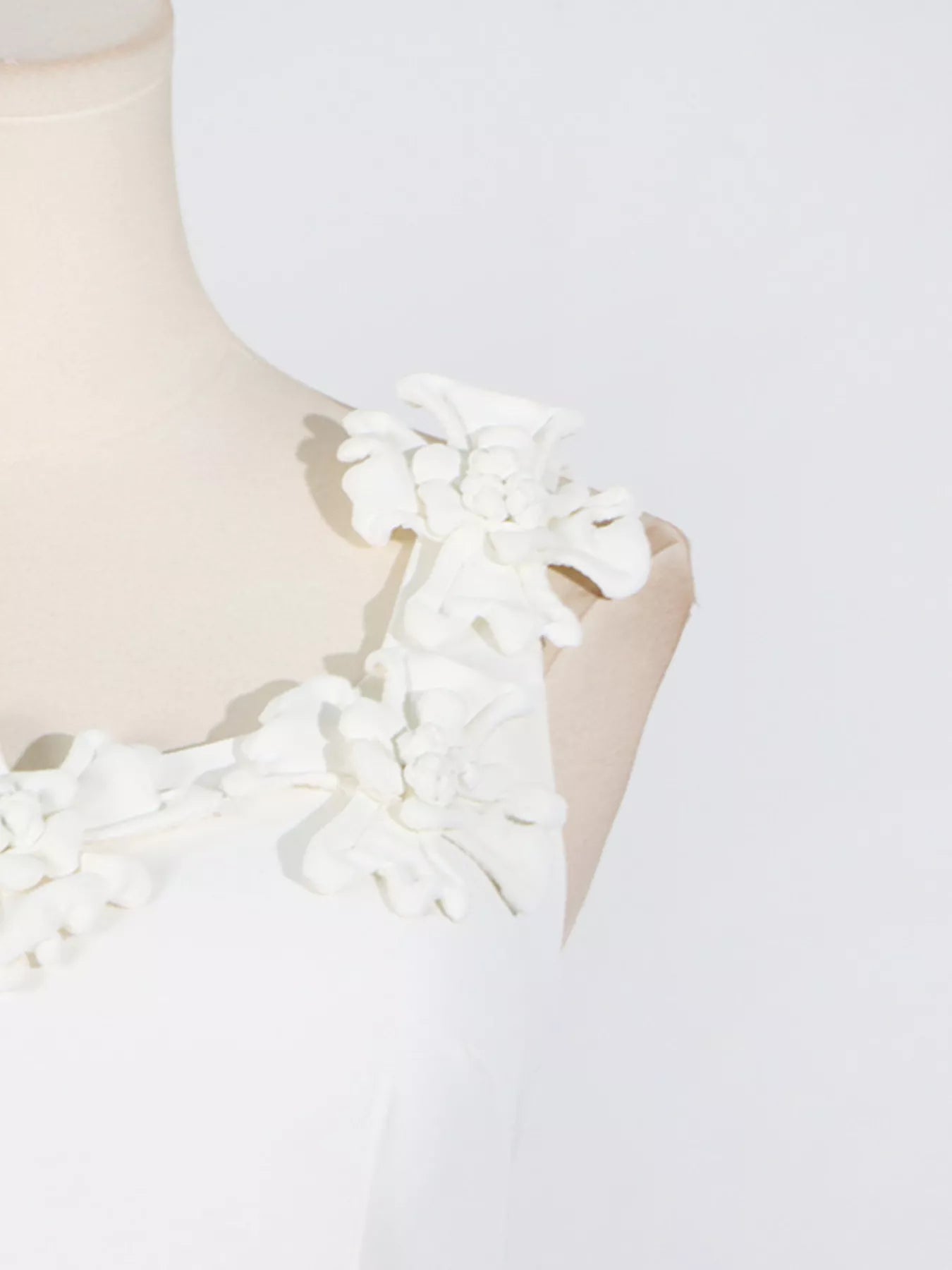 NEWYORKLISTED STYLE COLLECTION: White dress with floral details on a mannequin against a white background