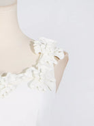 NEWYORKLISTED STYLE COLLECTION: White dress with floral details on a mannequin against a white background