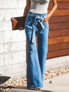 NEWYORKLISTED STYLE COLLECTION: Person wearing blue jeans with a white top, standing against a wooden wall.