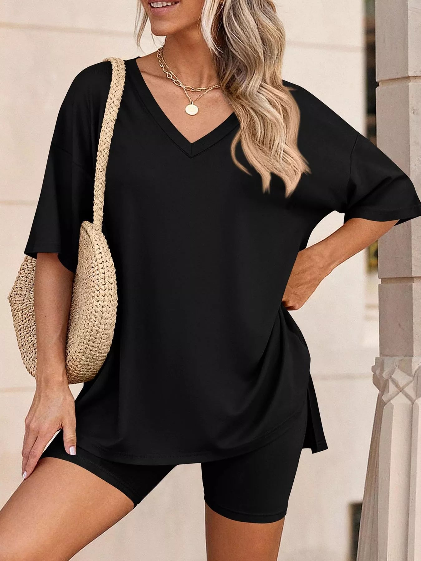 NEWYORKLISTED COMFORT COLLECTION: Woman wearing a black outfit with a straw bag against a neutral background