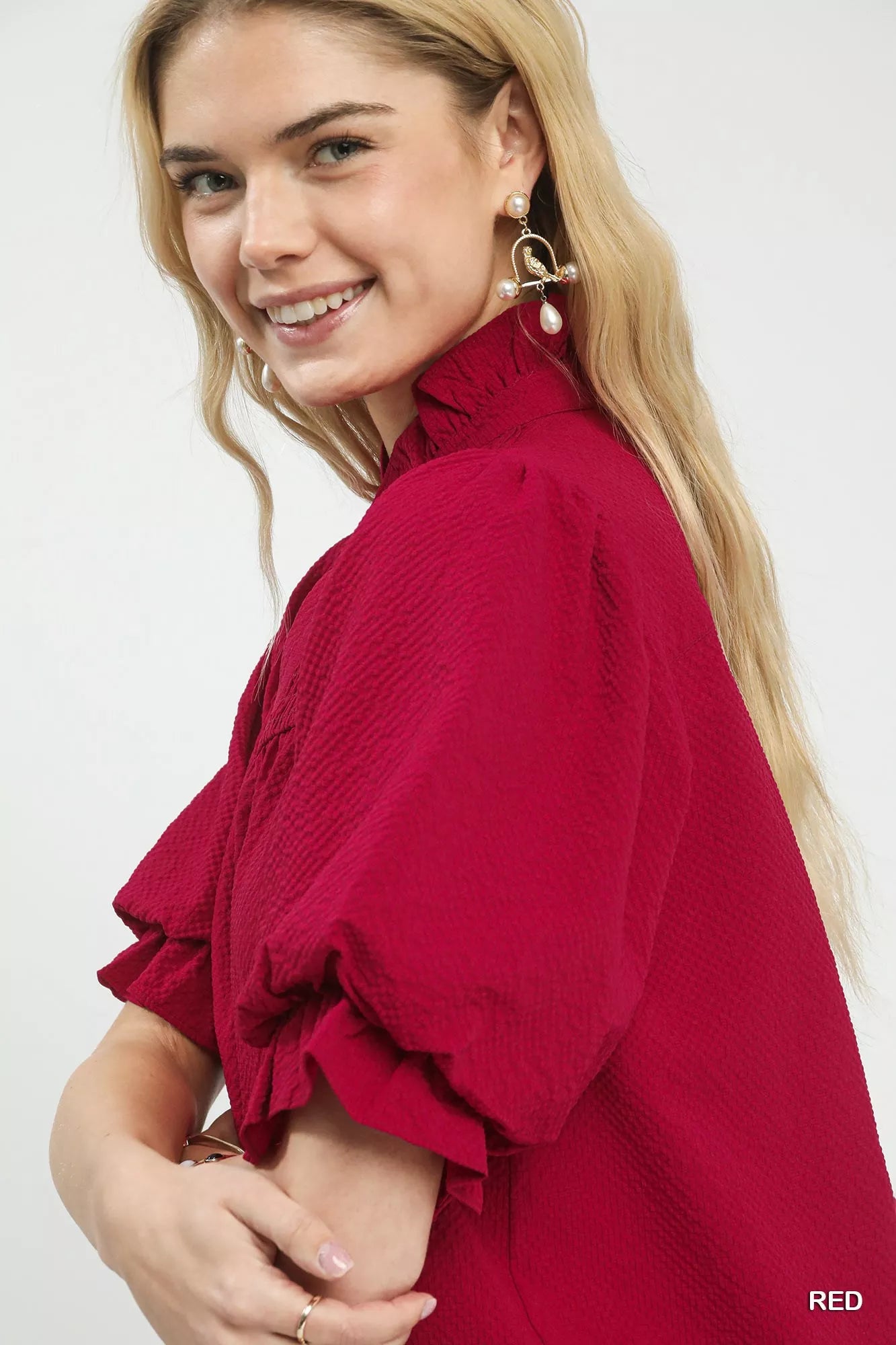 NEWYORKLISTED Style Collection: Woman wearing a red blouse with ruffled sleeves on a white background