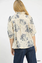 NEWYORKLISTED STYLE COLLECTION: Woman wearing a cream blouse with navy floral pattern and blue jeans on a white background