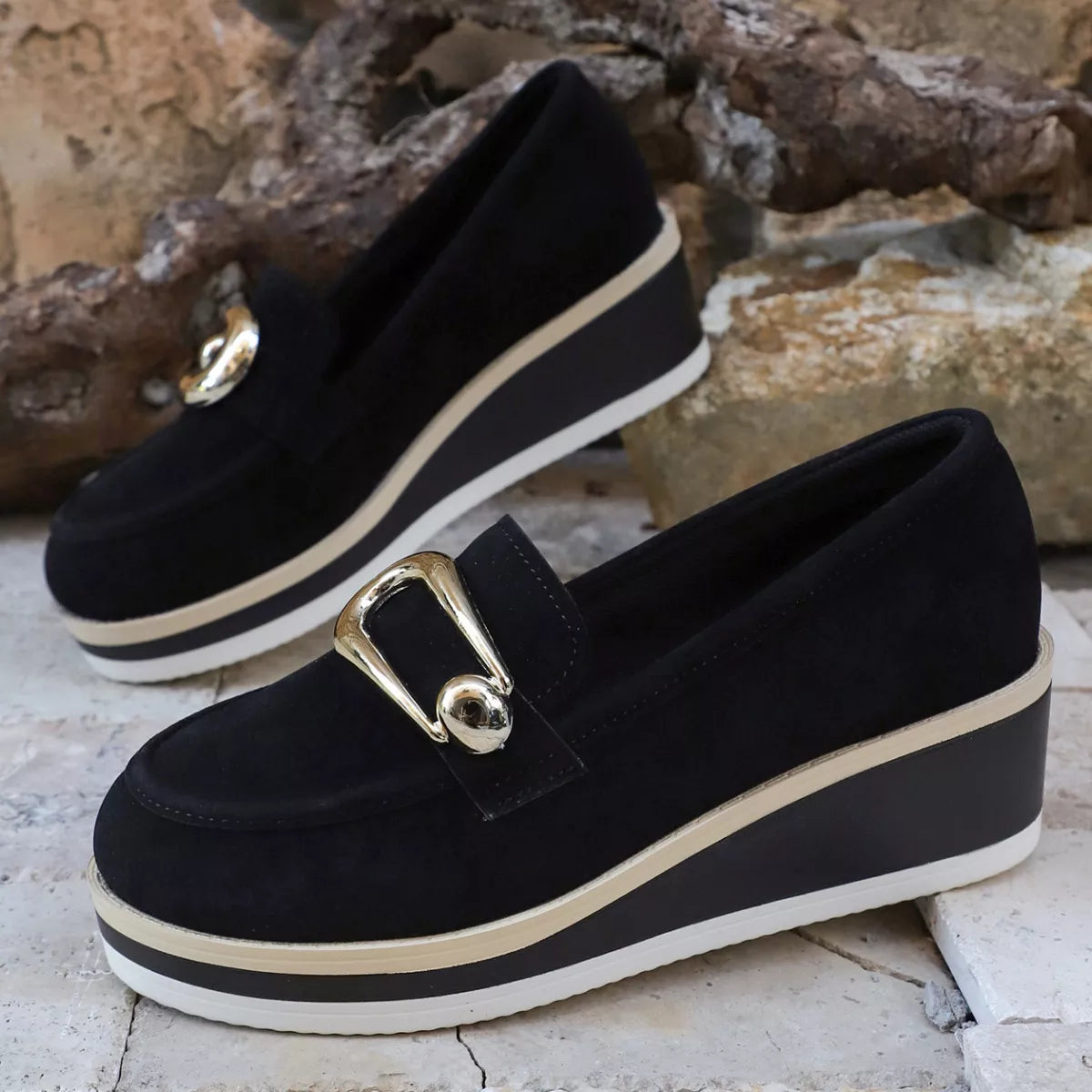 NEWYORKLISTED SHOE COLLECTION: Black loafers with gold buckles on a stone surface